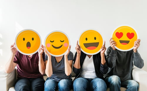 4 people holding emoji masks with excited and happy reactions