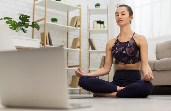 Woman meditating in front of laptop